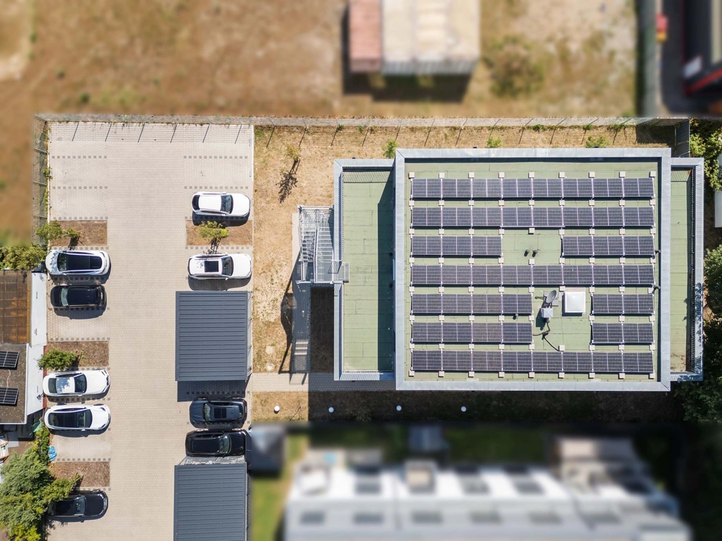 Drohnenaufnahme von Solarpaneelen auf dem Dach eines Gebäudes mit Parkplatz