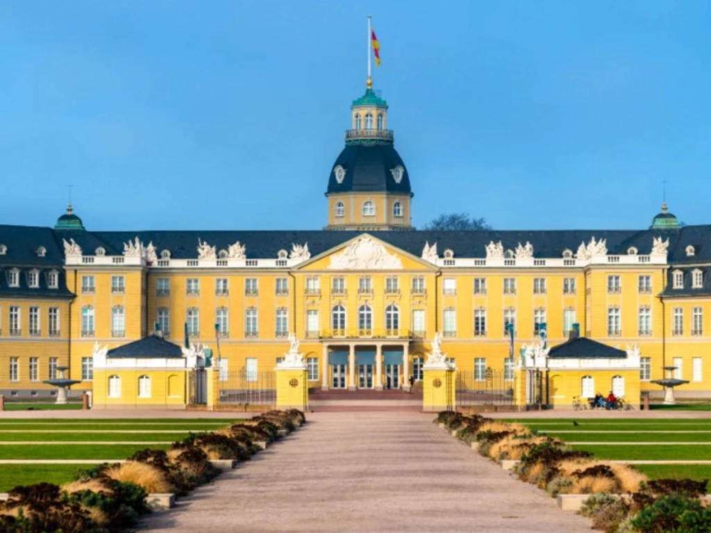 Schloss Karlsruhe bei Dämmerung mit beleuchtetem Hauptturm und Garten