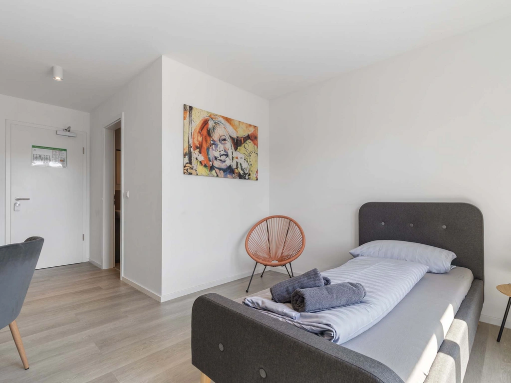 Modernes Schlafzimmer mit Einzelbett, Stuhl und bunter Wandkunst
