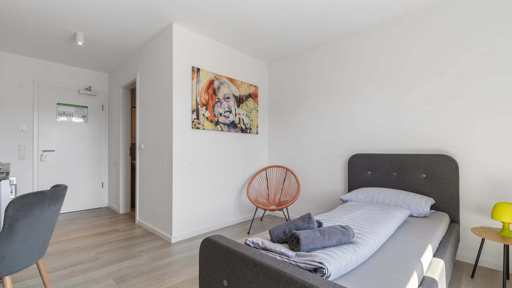 Modernes Schlafzimmer mit Einzelbett, Stuhl und bunter Wandkunst