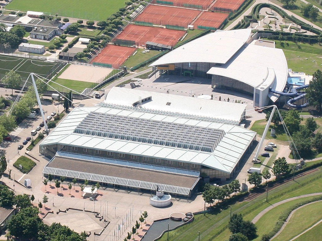Luftaufnahme eines Sportkomplexes mit Tennisplätzen und großen Hallen