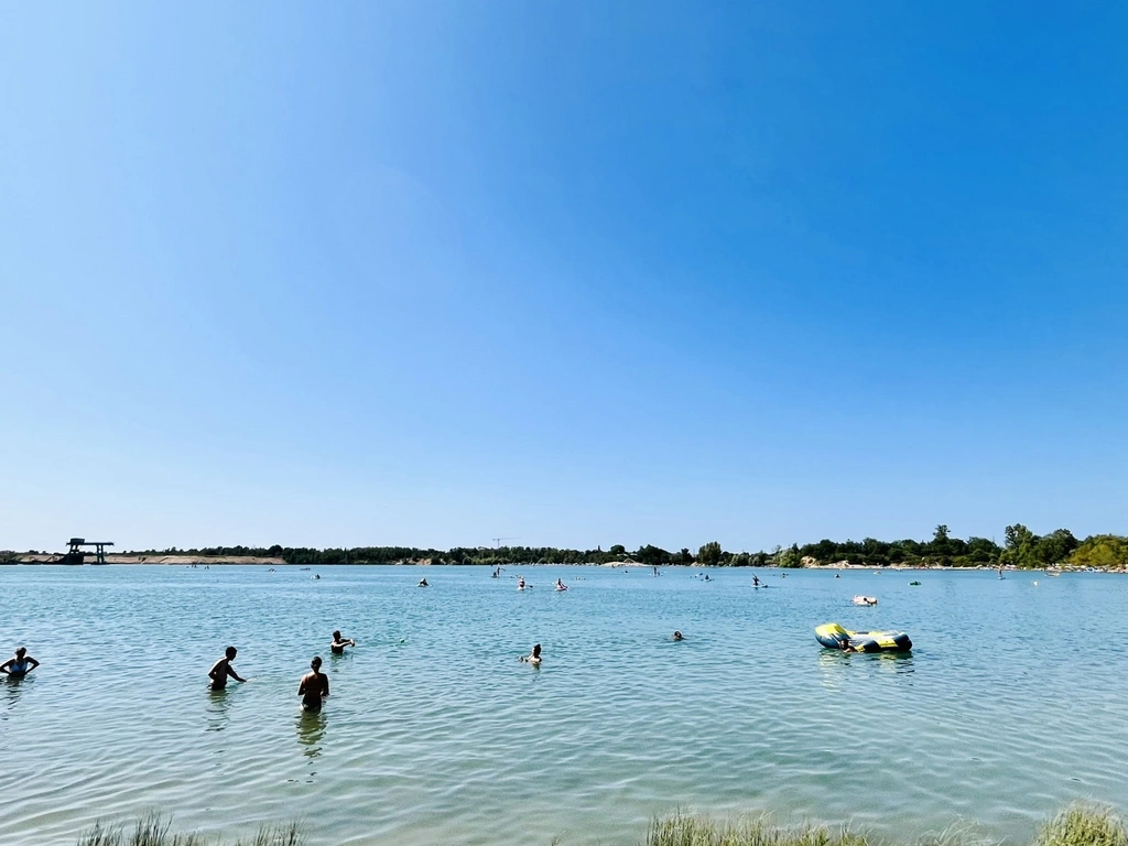 Menschen genießen einen sonnigen Tag im See beim Schwimmen und Stand-Up-Paddling