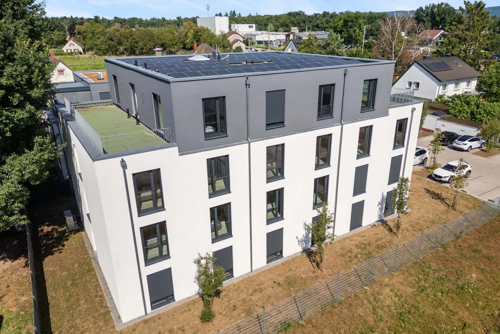 Modernes Wohngebäude mit Solarpanelen auf Dach und umliegenden Häusern