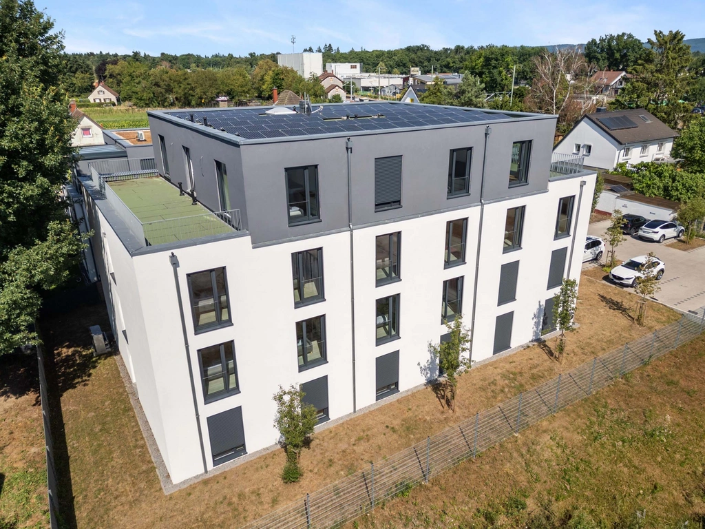 Modernes Wohngebäude mit Solarpanelen auf Dach und umliegenden Häusern