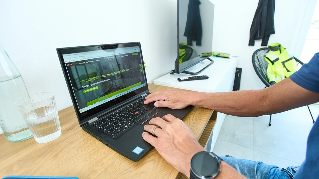 Person arbeitet an einem Laptop in einem hellen Zimmer