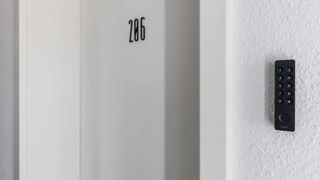 Tür mit Zimmernummer 206 und digitalem Türcodegerät an weißer Wand