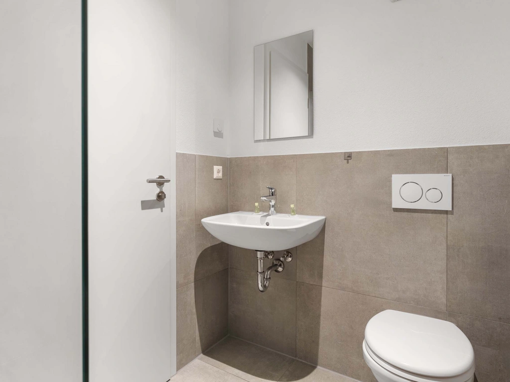 Kleine moderne Toilette mit Waschbecken und Spiegel an weißer Wand