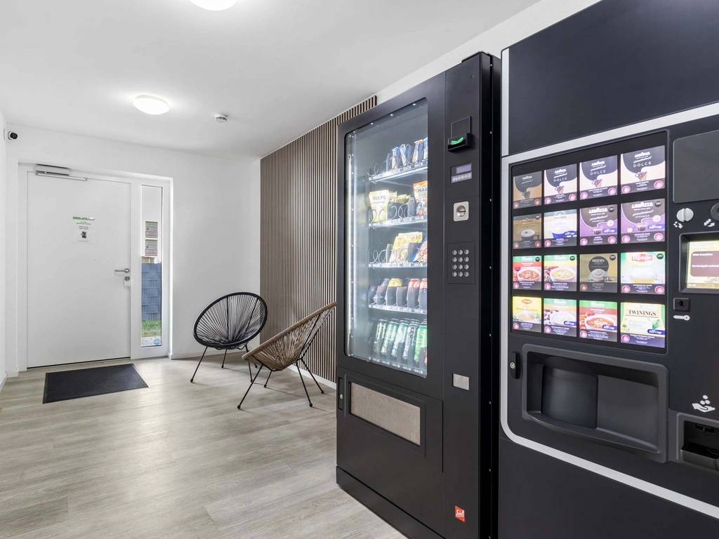 Moderne Snack- und Kaffeemaschinen im hellen Wartebereich mit Stühlen