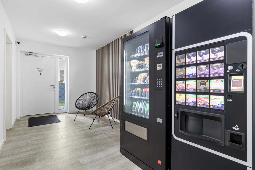 Moderne Snack- und Kaffeemaschinen im hellen Wartebereich mit Stühlen