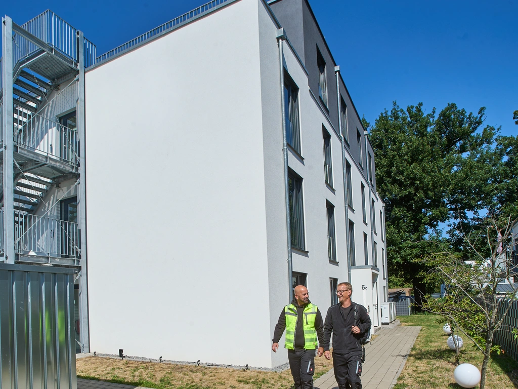 Zwei Männer gehen neben einem modernen Gebäude auf einem Gehweg