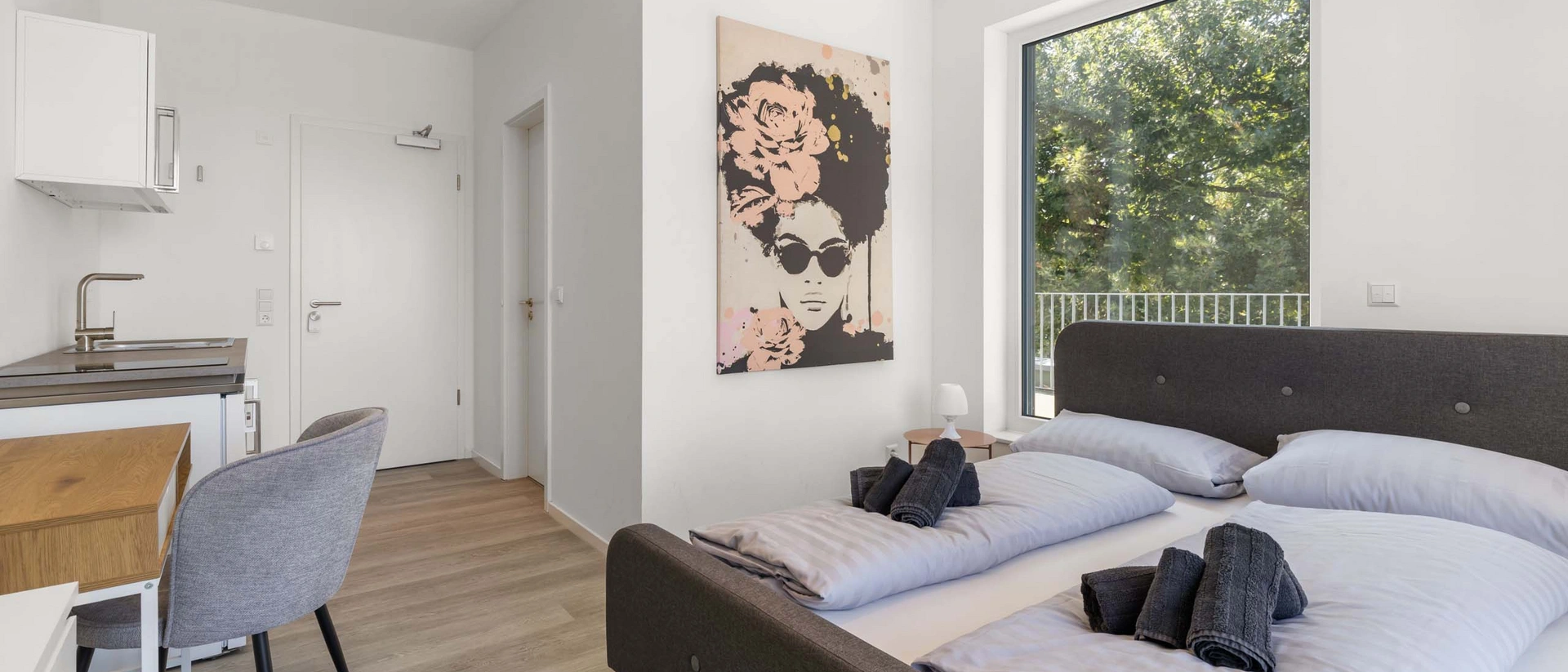 Minimalistisches, modernes Schlafzimmer mit Kunst, großem Fenster und Holzboden