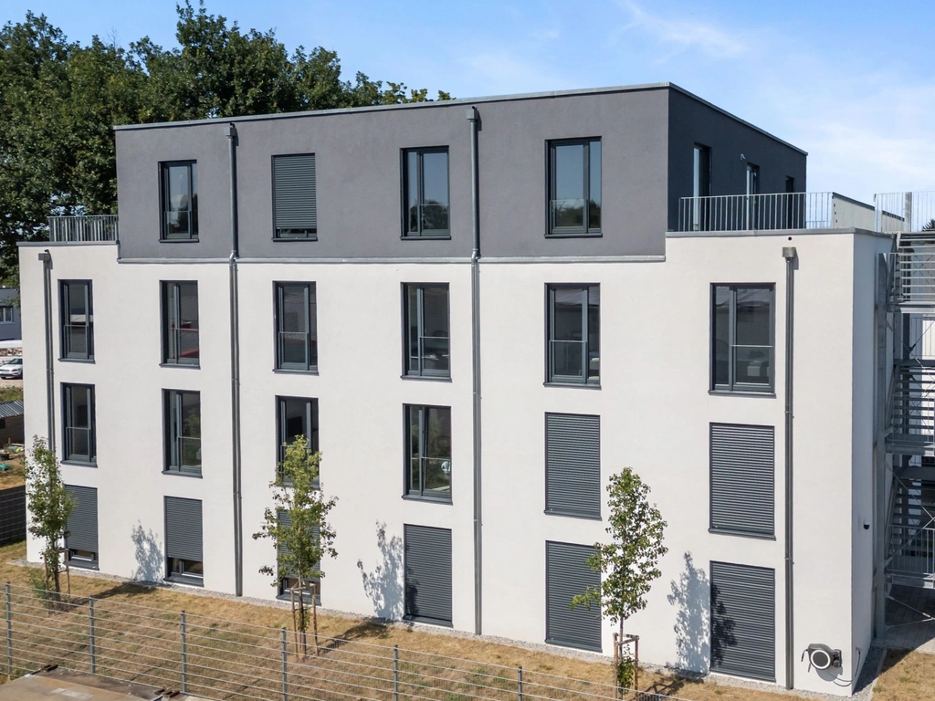 Modern multi-storey building with gray facade, windows, terrace and external staircase