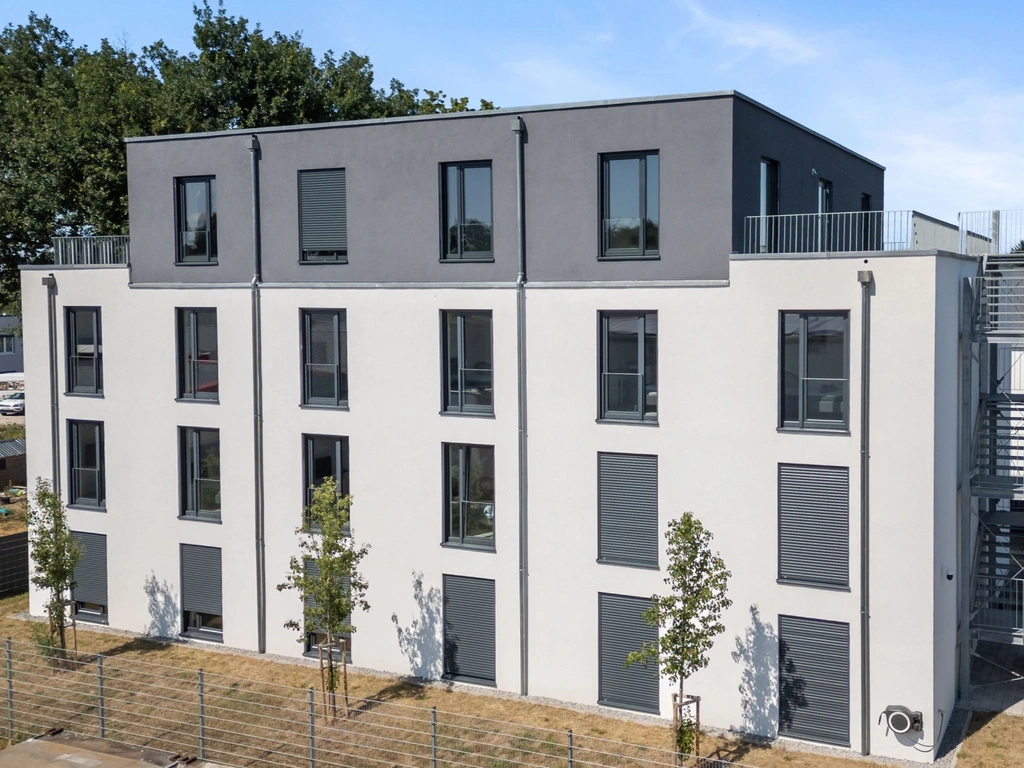 Modernes mehrstöckiges Gebäude mit grauer Fassade, Fenstern, Terrasse und Außentreppe