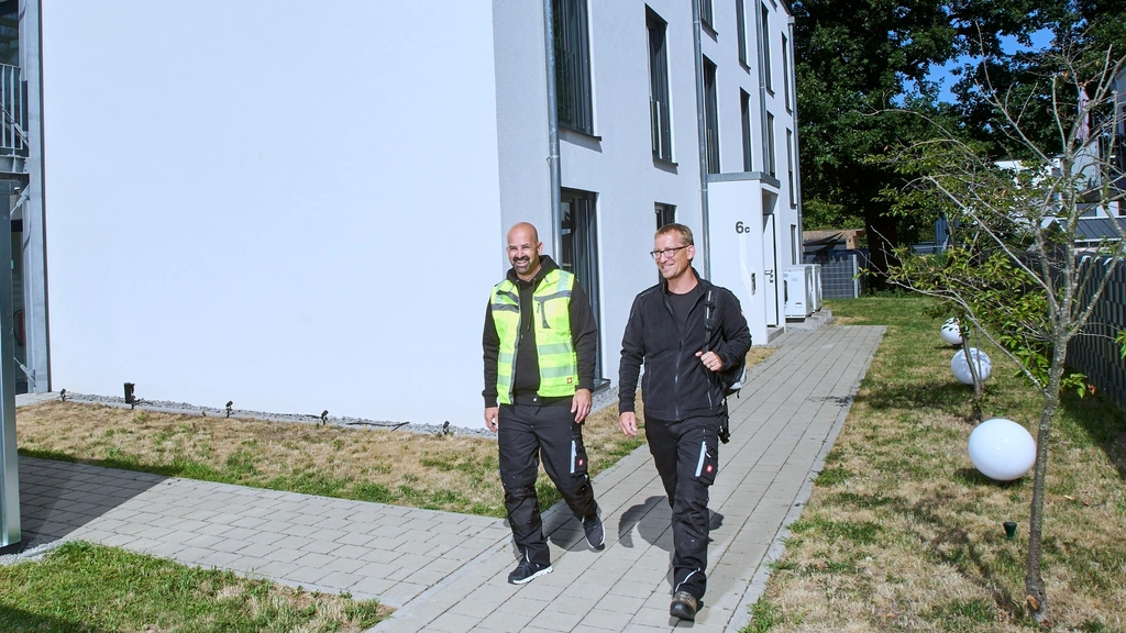 Zwei Männer gehen an einem modernen weißen Gebäude entlang