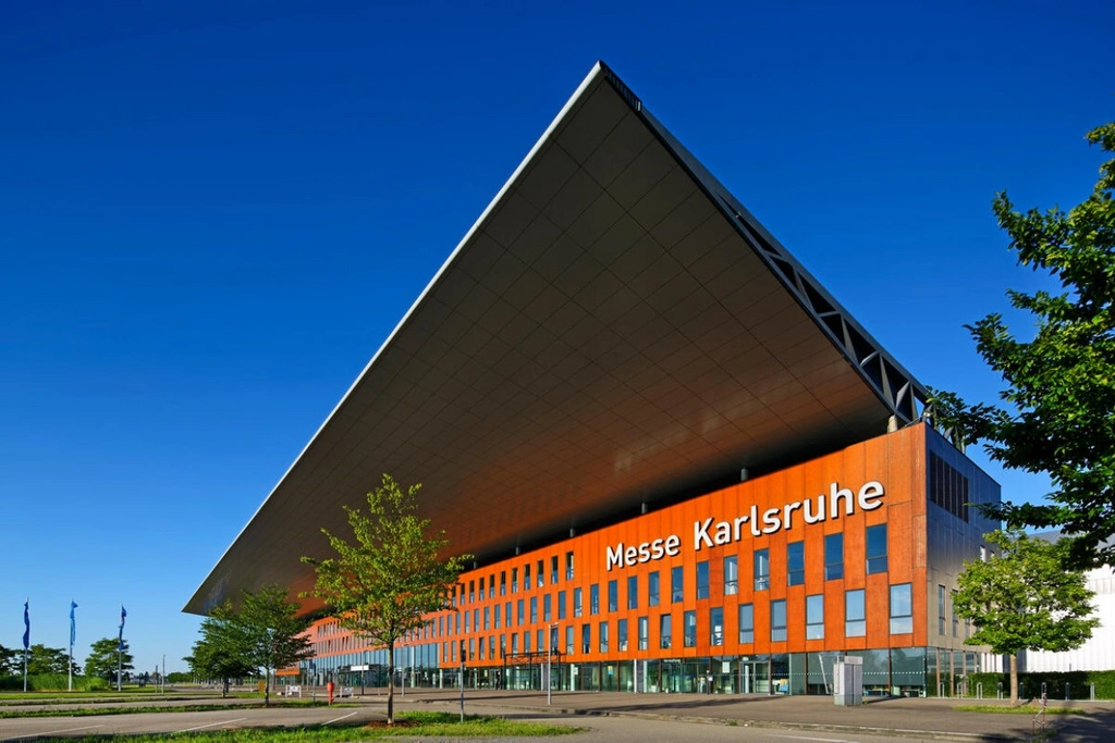 Außenansicht der Messe Karlsruhe mit markantem Vordach und orangefarbener Fassade