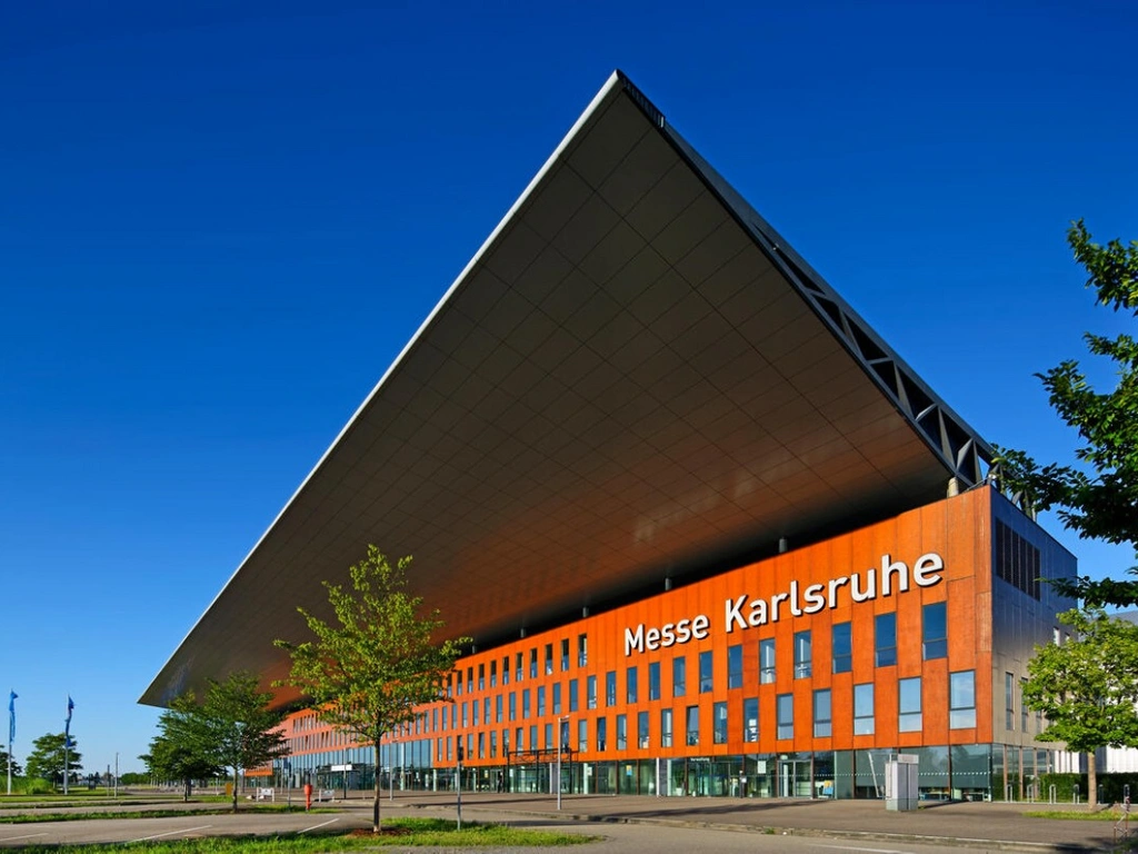 Außenansicht der Messe Karlsruhe mit markantem Vordach und orangefarbener Fassade