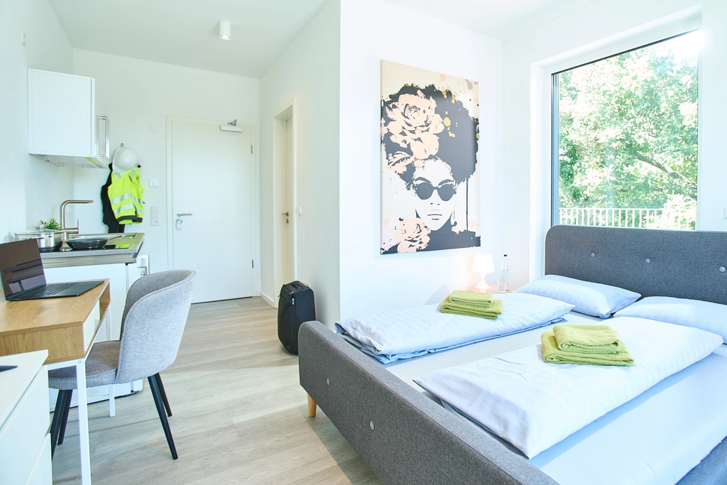 Helles Zimmer mit Doppelbett, Küchenzeile, Esstisch und großem Fenster