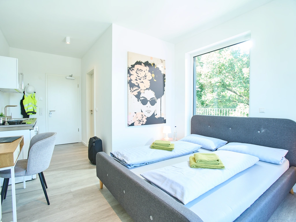 Helles Zimmer mit Doppelbett, Küchenzeile, Esstisch und großem Fenster