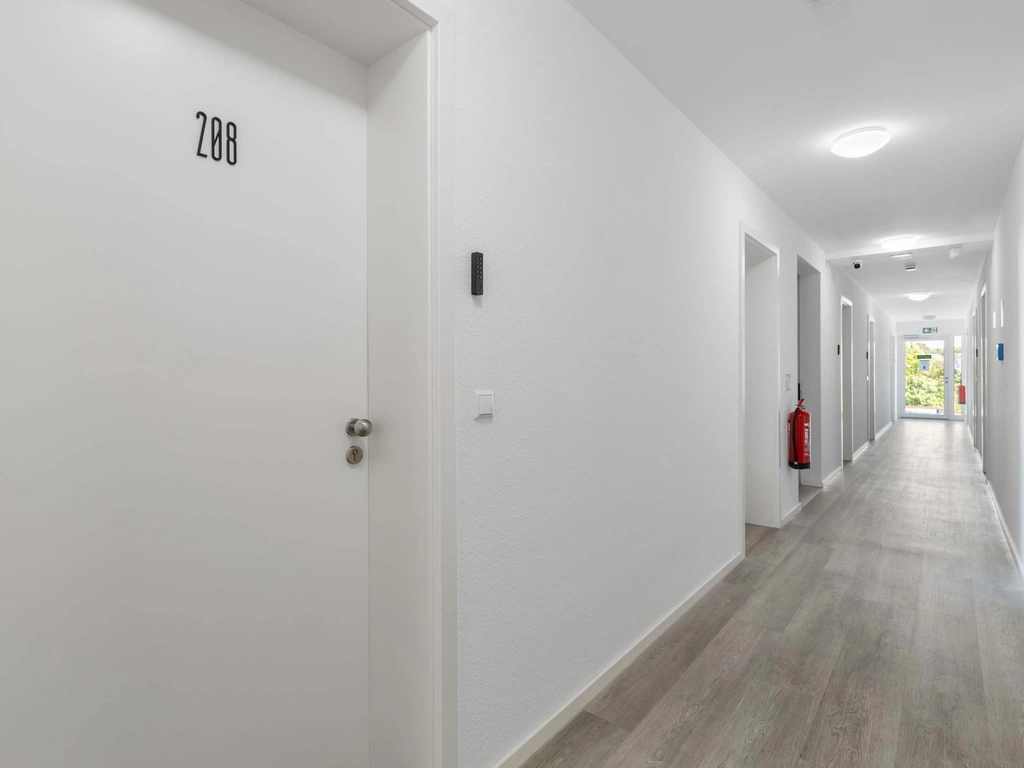 Heller Flur mit weißen Türen und Türnummer 208